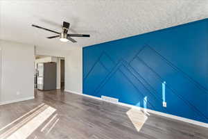 Unfurnished room with wood finished floors, baseboards, a textured ceiling, and ceiling fan
