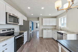Kitchen with appliances with stainless steel finishes, a sink, white cabinetry, a textured ceiling, and recessed lighting