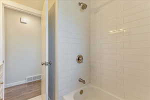 Bathroom featuring wood finished floors, shower / tub combination, and baseboards