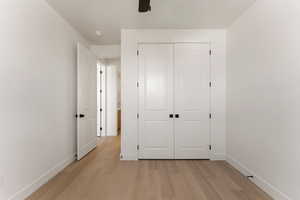 Unfurnished bedroom featuring light wood-style flooring, baseboards, a closet, and a ceiling fan
