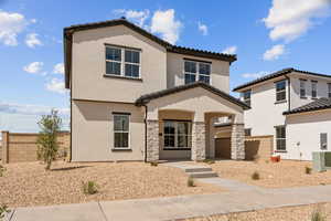View of front of house with a tiled roof, stucco siding, fence, and stone siding