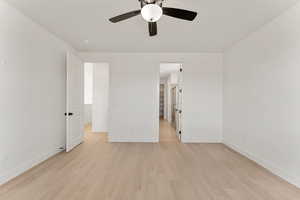 Unfurnished bedroom featuring light wood-style floors, baseboards, a walk in closet, and ceiling fan