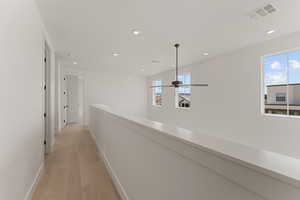 Corridor with light wood-style flooring, baseboards, recessed lighting, and an upstairs landing
