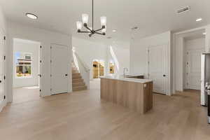 Kitchen featuring a center island with sink, recessed lighting, light wood-style flooring, a chandelier, and a sink