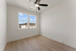 Spare room featuring baseboards, light wood-type flooring, and a ceiling fan