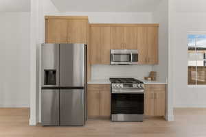Kitchen featuring appliances with stainless steel finishes, light countertops, baseboards, and light wood-style floors