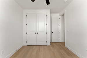 Unfurnished bedroom with baseboards, light wood finished floors, a closet, and ceiling fan