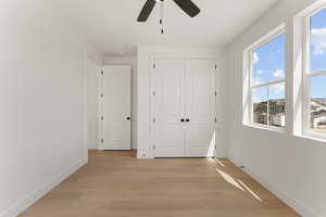 Unfurnished bedroom featuring light wood-type flooring, baseboards, a closet, and a ceiling fan