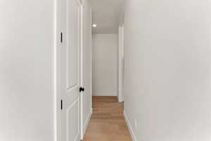 Hallway with light wood-style floors, baseboards, and recessed lighting