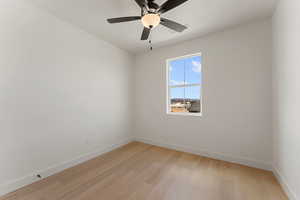 Spare room with baseboards, light wood-style floors, and ceiling fan