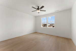 Spare room with light wood finished floors, ceiling fan, and baseboards