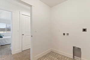 Clothes washing area featuring hookup for an electric dryer, washer hookup, and baseboards