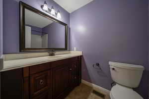 Full bath featuring toilet, vanity, baseboards, and tile patterned floors