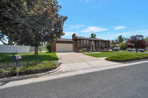 View of front of home featuring concrete driveway, an attached garage, brick siding, and a chimney