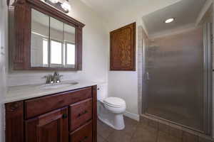 Bathroom featuring vanity, toilet, a stall shower, and tile patterned floors