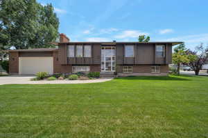 Raised ranch with a garage, brick siding, and concrete driveway