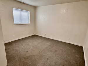 Empty room with dark carpet and baseboards