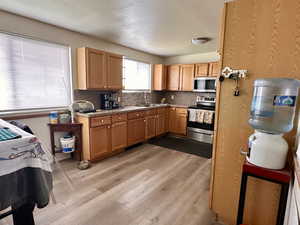 Kitchen featuring stainless steel appliances, a sink, light wood-style flooring, backsplash, and a textured ceiling