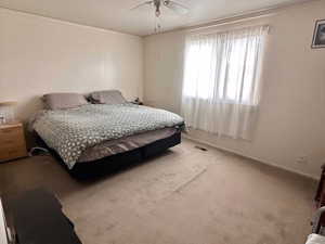 Bedroom with light colored carpet, crown molding, baseboards, and a ceiling fan