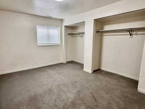 Unfurnished bedroom with two closets, carpet flooring, and baseboards