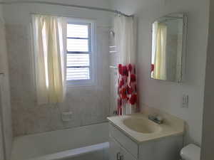 Full bathroom with toilet, vanity, and shower / tub combo