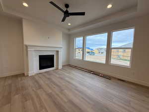 Unfurnished living room with a tray ceiling, ceiling fan, light wood-style flooring, baseboards, and recessed lighting