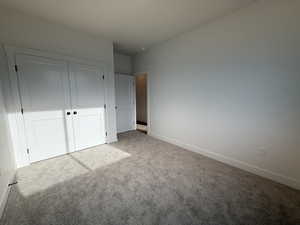 Unfurnished bedroom featuring carpet floors, baseboards, and a closet