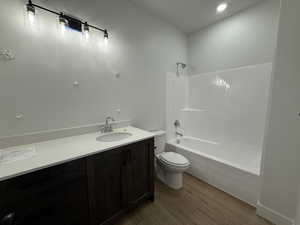 Full bath with wood finished floors, toilet, vanity, and shower / bath combination