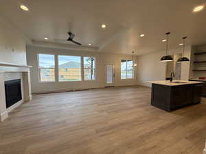 Unfurnished living room featuring a sink, light wood-type flooring, a fireplace, recessed lighting, and ceiling fan