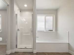 Full bath with a shower stall, vanity, a bath, and baseboards