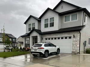 Craftsman-style home with a garage, driveway, and stone siding