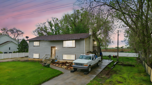 Back of property at dusk featuring a chimney and concrete driveway