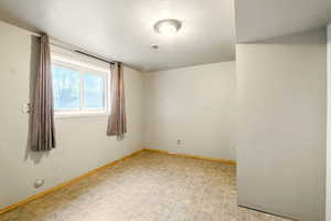 Unfurnished room featuring baseboards, a textured ceiling, and light flooring