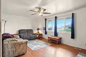 Living room featuring wood finished floors, a ceiling fan, and baseboards
