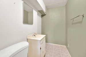 Bathroom with toilet, vanity, tile patterned flooring, and baseboards