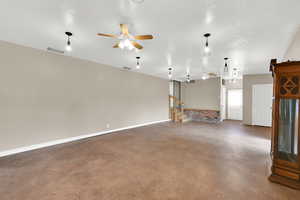 Unfurnished living room with ceiling fan, finished concrete floors, and baseboards
