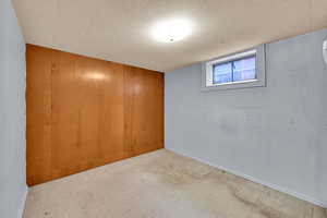 Basement featuring tile patterned floors, wood walls, and baseboards