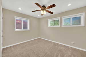 Carpeted spare room featuring a ceiling fan, baseboards, and recessed lighting