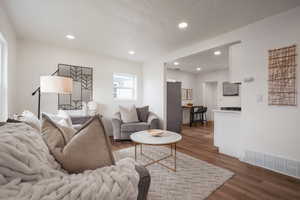 Living area featuring recessed lighting, dark wood-type flooring, and a textured ceiling