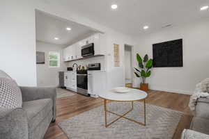 Living area featuring wood finished floors, recessed lighting, bar area, and baseboards