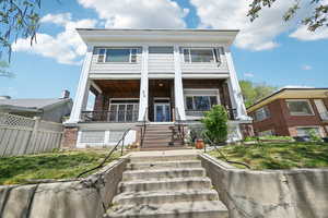 View of front facade featuring covered porch, stairs, brick siding, fence, and french doors