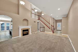 Unfurnished living room featuring carpet floors, tile patterned flooring, baseboards, a towering ceiling, and recessed lighting
