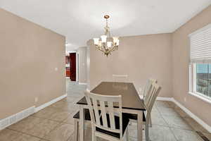 Dining space featuring a chandelier, light tile patterned floors, and baseboards