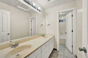 Bathroom with double vanity, tile patterned flooring, and baseboards