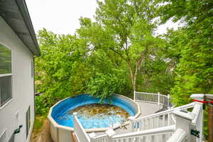 View of pool featuring a wooden deck and a jacuzzi