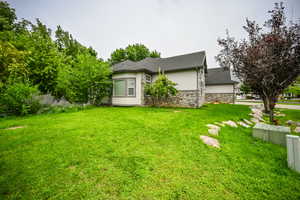 View of home's exterior with stucco siding, stone siding, and a lawn