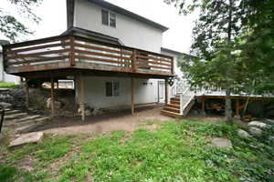 Back of property featuring a deck, stucco siding, and stairs