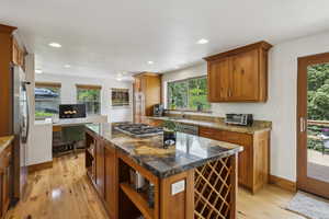 Kitchen with appliances with stainless steel finishes, a sink, light wood-style floors, open shelves, and plenty of natural light