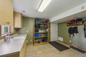 Laundry room with a sink, baseboards, light tile patterned floors, and a textured ceiling