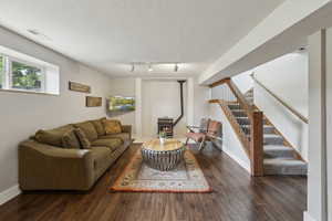 Living area featuring stairs, wood finished floors, baseboards, and rail lighting
